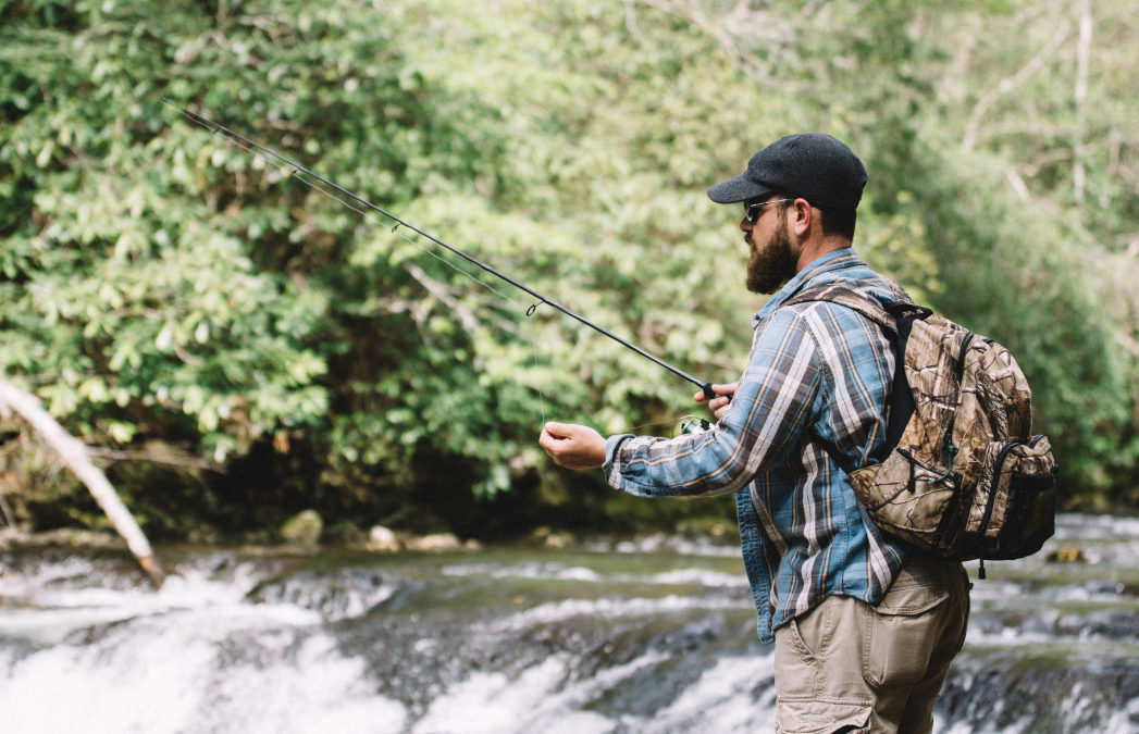 man fishing in the woods with a backpack that has crockett creek jerky in it for a snack while fishing