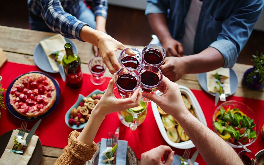 friends cheers-ing with wine over thanksgiving dinner table