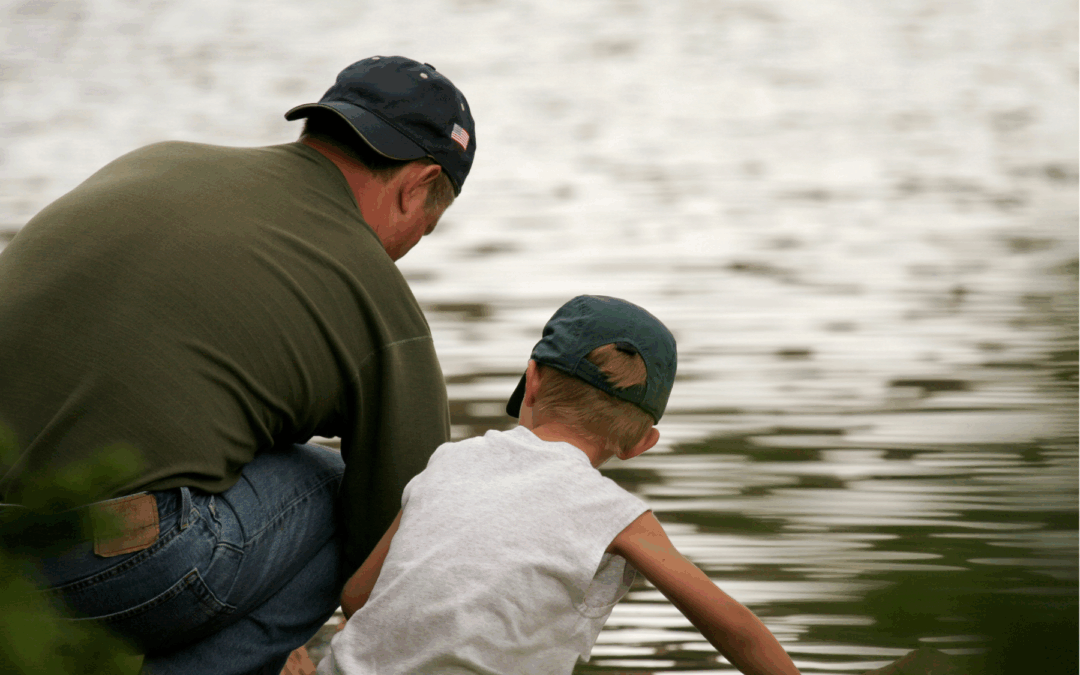 Photo of a man and young child, presumably father and son looking out over the water